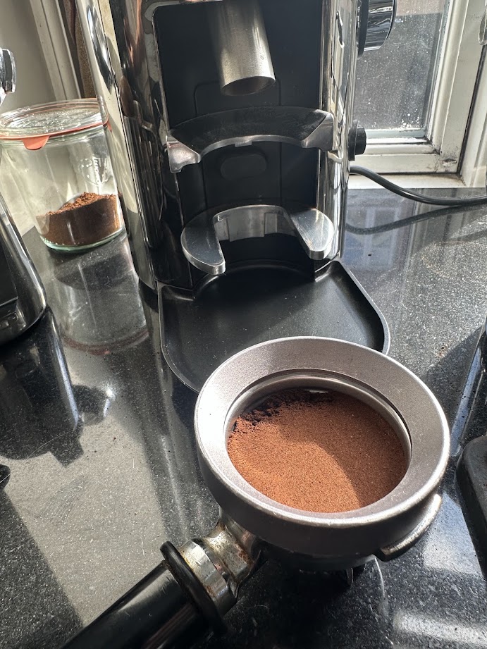 An electric coffee grinder beside an espresso portafilter